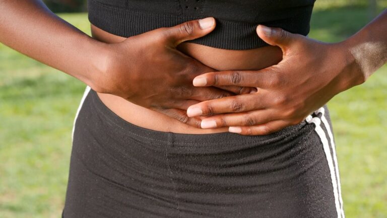 Person holding their stomach, illustrating bloating and abdominal discomfort after eating