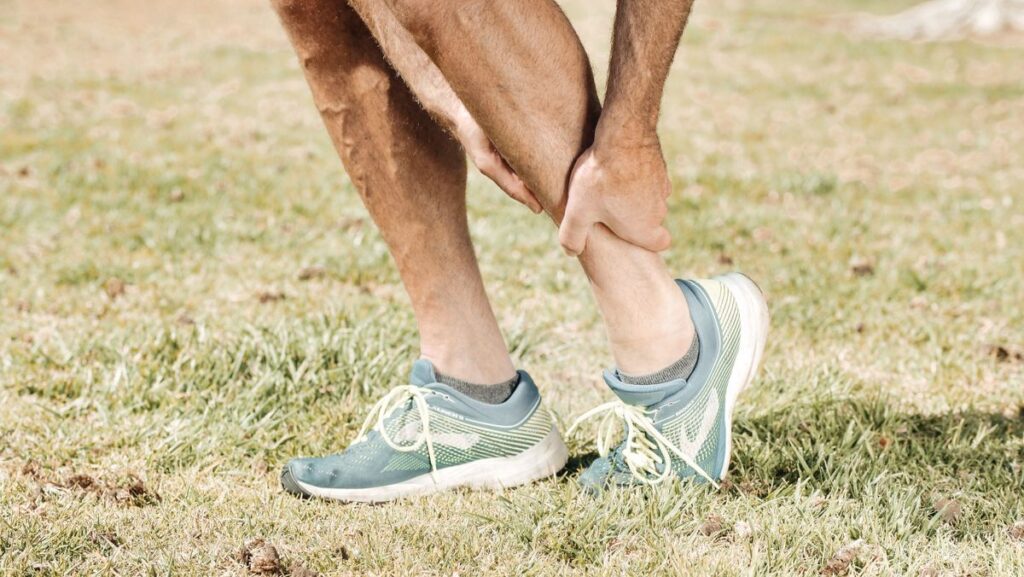Runner holding a painful lower leg and ankle after walking or exercise