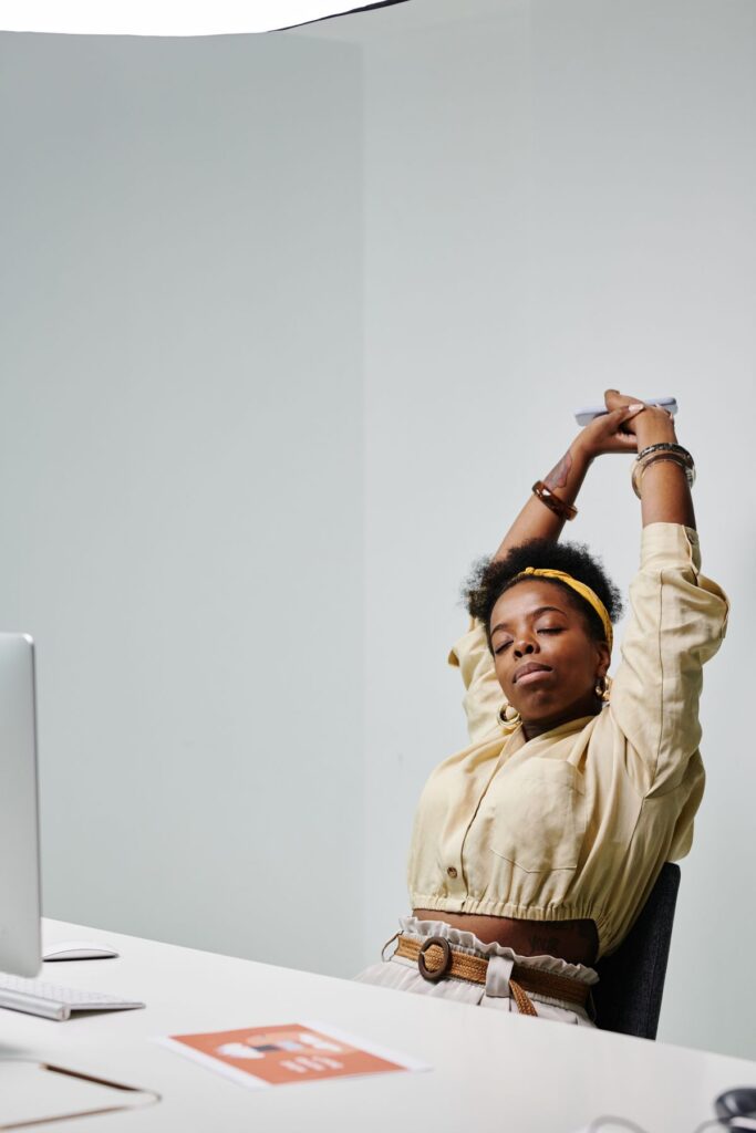 Office worker stretching at a desk to ease neck and shoulder tension after sitting