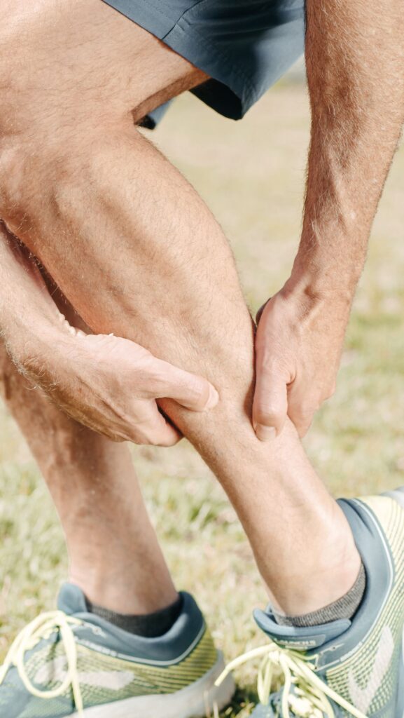 Runner massaging a sore calf outdoors after exercise