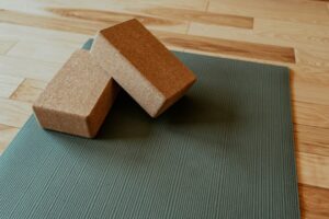 Two cork yoga blocks resting on a green exercise mat on a wooden floor